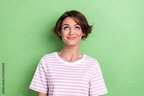 Photo of optimistic bob hairdo millennial lady look up wear white striped t-shirt isolated on green color background © deagreez
