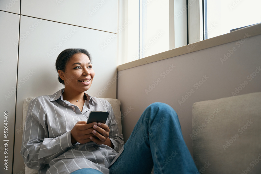 Beautiful positive female with smartphone is spending time in her flat Beautiful positive female with smartphone is spending time in her flat