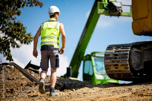 Bauarbeiter auf Baustelle vor Fahrzeugen