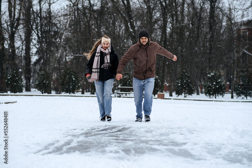 Winter couple activities. Winter Date Ideas to Cozy Up. Cold season dates for couples. Young couple in love waking, skating and having fun in winter snowy park. photo