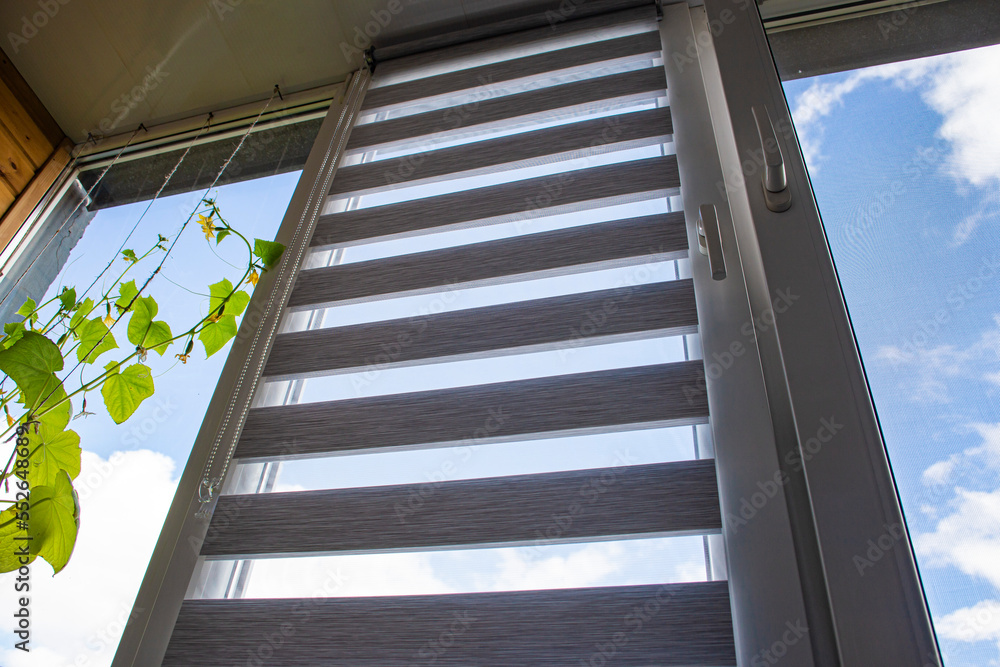 a plastic window open for ventilation with a roller blind and a mosquito net against the blue sky a plastic window open for ventilation with a roller blind and a mosquito net against the blue sky