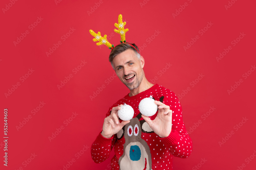 cheerful guy holding xmas decoration balls on red background. happy new year.