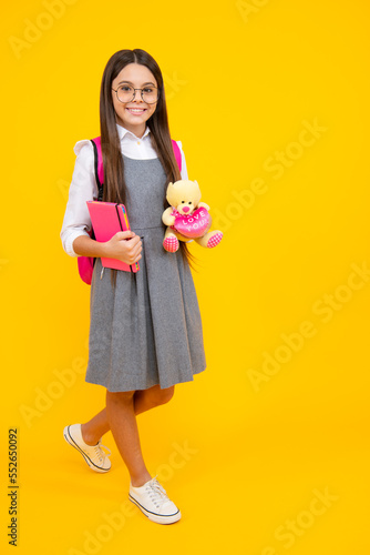 School girl hold toy. School children with favorite toys on yellow isolated background. Childhood concept.