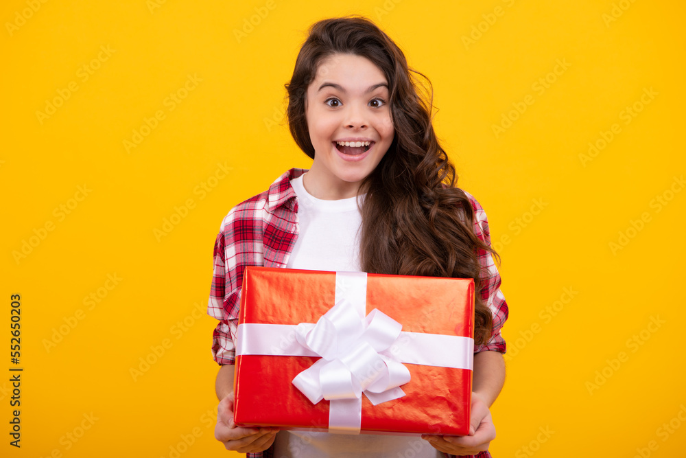 Amazed teenager. Teenager child holding gift box on yellow isolated background. Gift for kids birthday. Christmas or New Year present box. Excited teen girl. Amazed teenager. Teenager child holding gift box on yellow isolated background. Gift for kids birthday. Christmas or New Year present box. Excited teen girl.