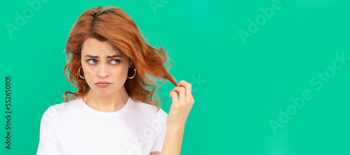 unhappy redhead woman with curly hair on blue background, disappointment. Woman isolated face portrait, banner with copy space. © Olena