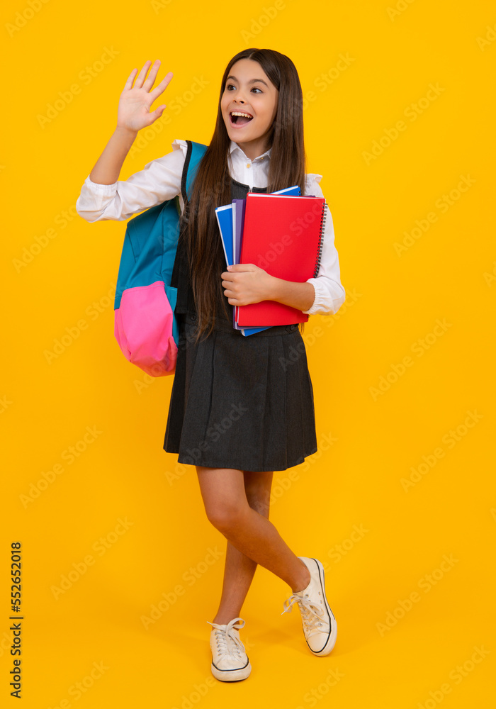 Schoolchild, teenage student girl with school bag backpack hold book on yellow isolated studio background. Children school and education concept. Schoolchild, teenage student girl with school bag backpack hold book on yellow isolated studio background. Children school and education concept.