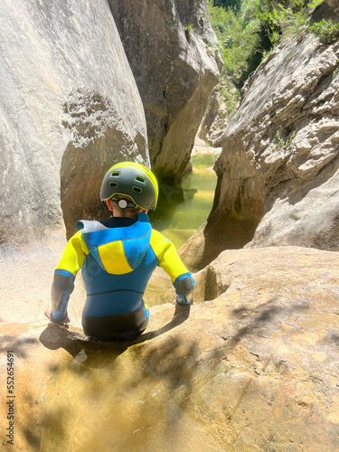 Adrenaline sport - Canyoning. Child with neoprene in mountain ravine