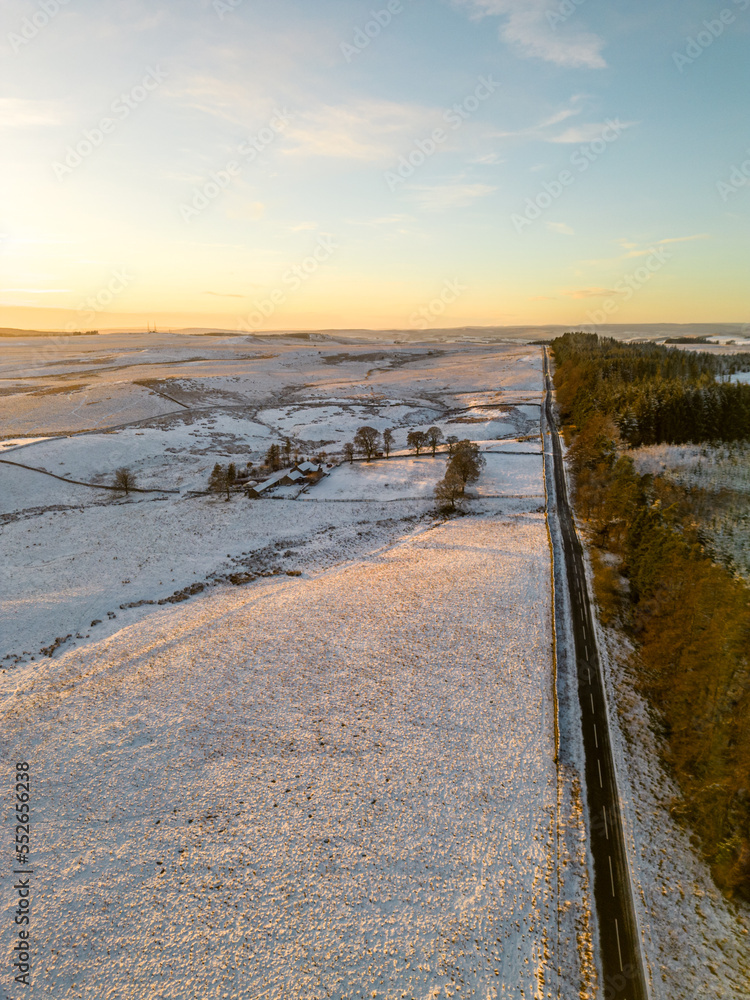 Long empty road through snowy winter landscape in Northumberland, UK