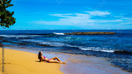 Fototapeta Naklejka Na Ścianę i Meble -  beautiful girl in a bikini lies on the sand on a Caribbean beach in Costa Rica; sunbathing on a paradise beach by the Caribbean sea, beach vacation in tropical Costa Rica