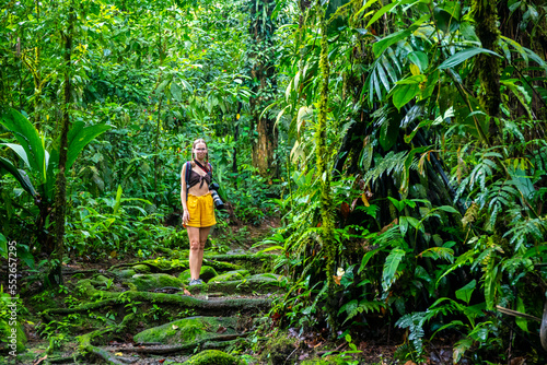 girl photographer walks through dense Costa Rican tropical rainforest; hiking through the jungle in Costa Rica's braulio carrillo national park near san jose