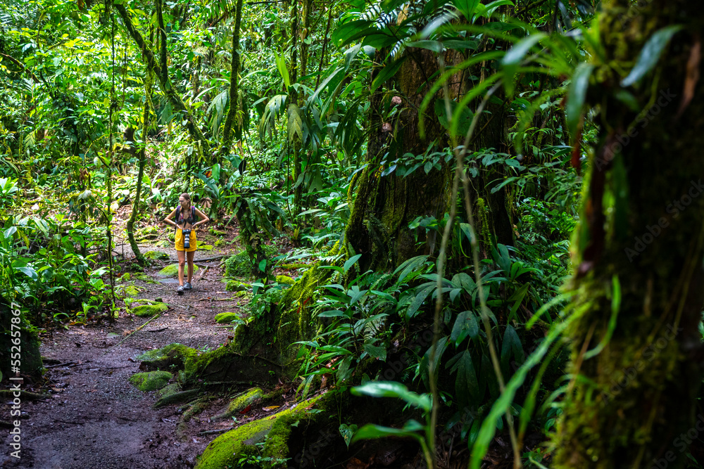 Obraz premium girl photographer walks through dense Costa Rican tropical rainforest; hiking through the jungle in Costa Rica's braulio carrillo national park near san jose
