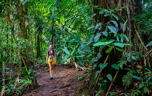 girl photographer walks through dense Costa Rican tropical rainforest; hiking through the jungle in Costa Rica\'s braulio carrillo national park near san jose