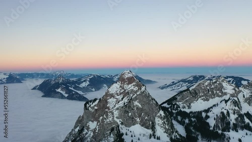 Stunning drone video in the middle of the Swiss Alps on a beautiful morning with a pink horizon and a sea of ​​fog in the background. photo