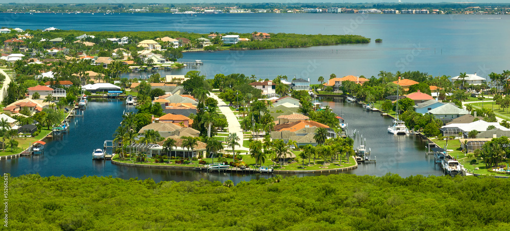 Aerial view of rural private houses in remote suburbs located near Florida wildlife wetlands with green vegetation on sea bay shore. Living close to nature concept