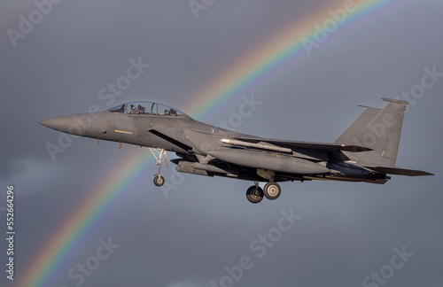fighter jet flying over with missiles on way to combat mission. Modern F-15 fighter jets and Airforce pilots on deployment for air defence. Dramatic military fighter jet with a rainbow