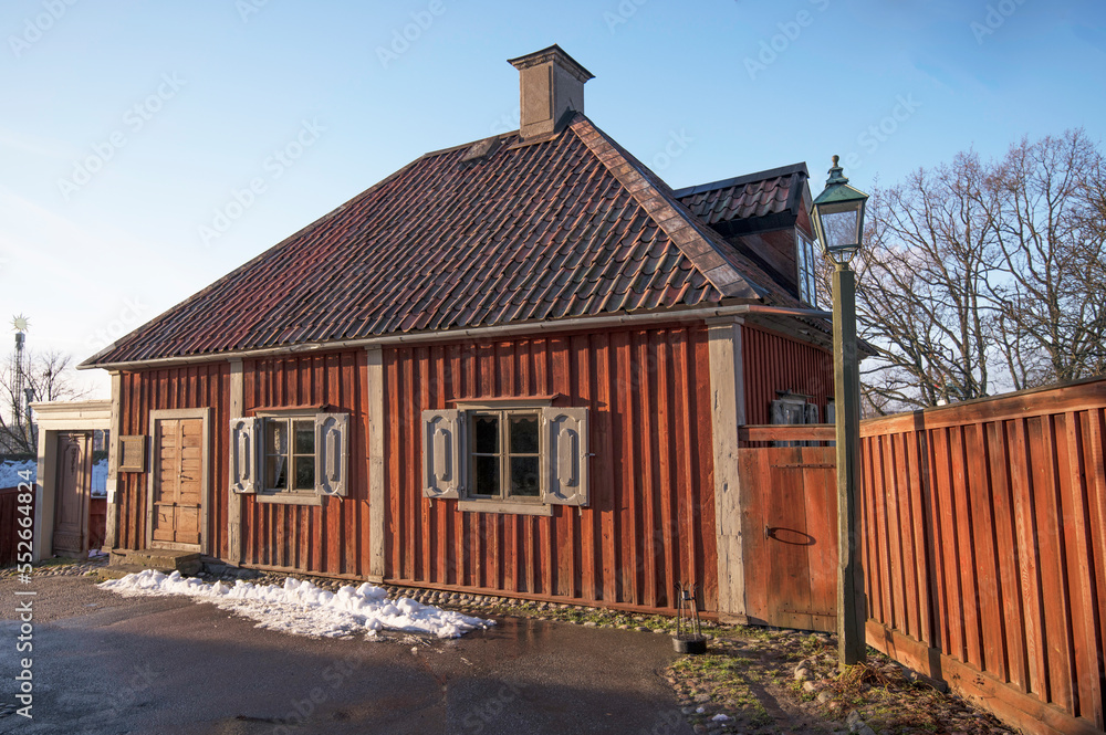 Old 1800s red banking house with dorm and chimney on a tile roof in a park a pale sun winter day in Stockholm Old 1800s red banking house with dorm and chimney on a tile roof in a park a pale sun winter day in Stockholm