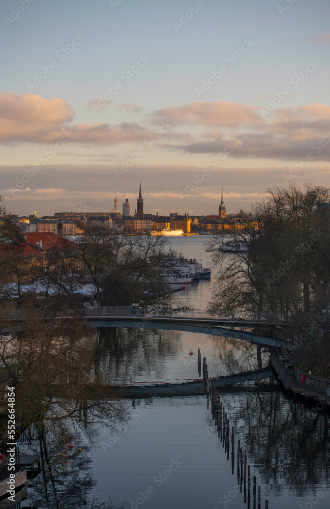 The canal Pålsundet and skyline with churches and old houses in the old town Gamla Stan a winter day with dark clouds and low sun in Stockholm