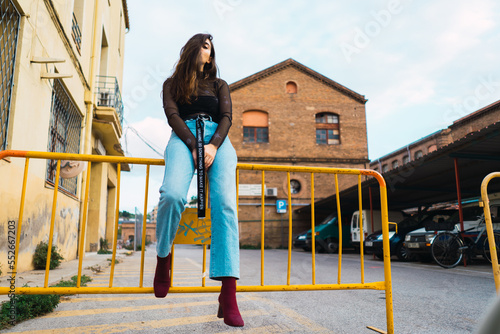 Φωτογραφία Low angle shot of a young model sitting over a yellow temporary perimeter fence