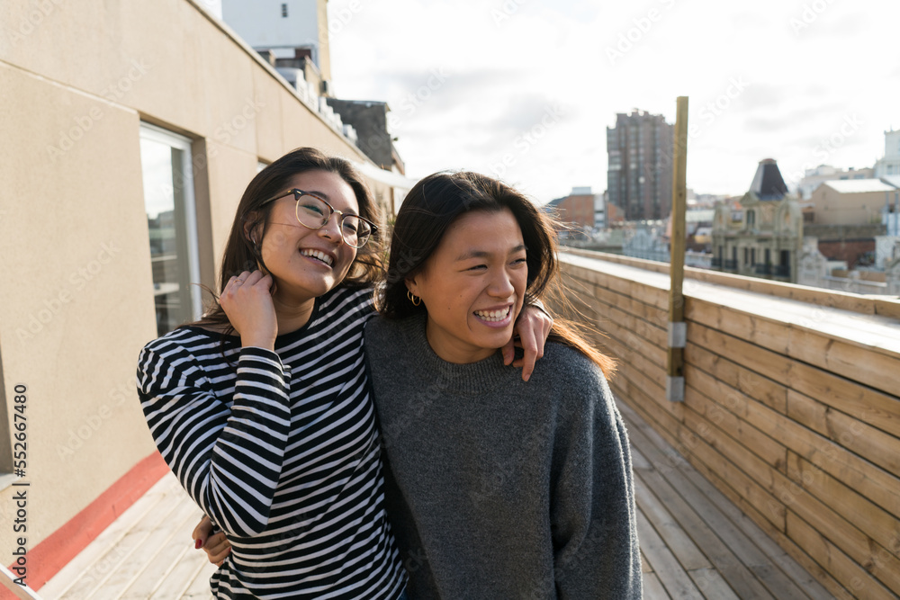 Two young Chinese women embracing and posing on balcony. Two young Chinese women embracing and posing on balcony.