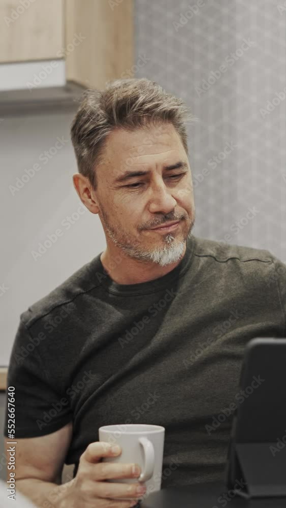 Man working with tablet computer in home office. Sitting at coffee table, drinking. Online in cafe. Man working with tablet computer in home office. Sitting at coffee table, drinking. Online in cafe.