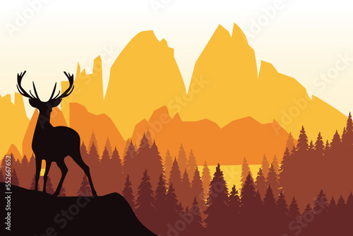 Deer with antlers posing on the top of the hill with mountains and the forest in the background.