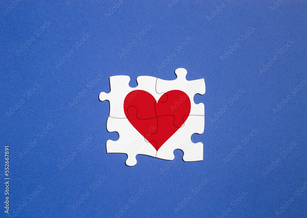 concept of polyamory. copy space. white puzzle pieces with red heart on blue background.