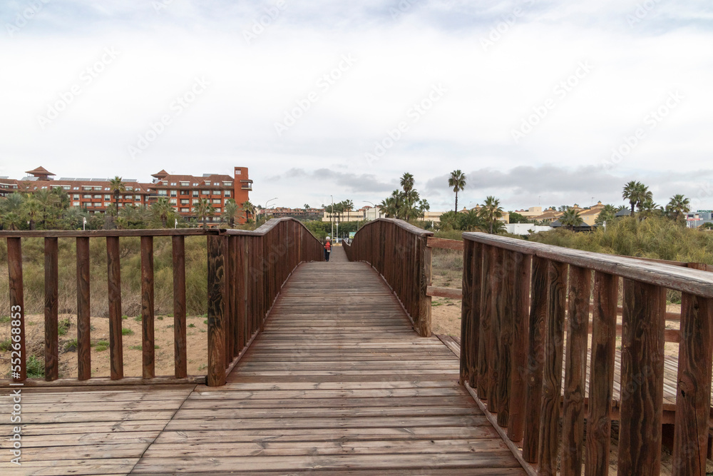 Senior woman with walking sticks hiking down a wooden walkway. Senior people lifestyle concept.