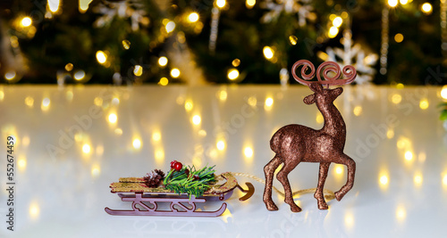 The raindeer is standing on a Christmas background with sled. © Olesya
