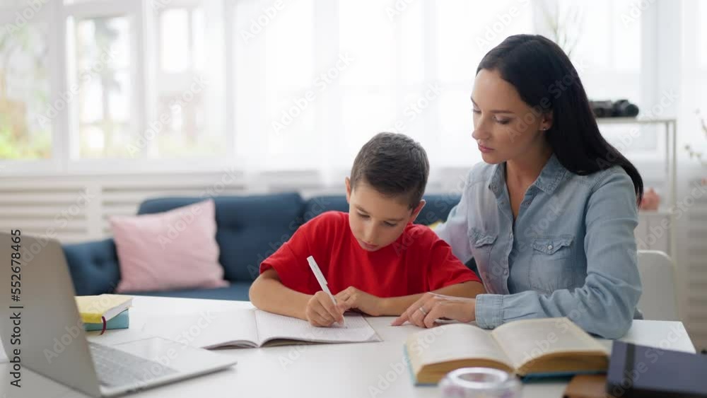 Schoolboy doing homework with his mother's help, child and parent relationship Schoolboy doing homework with his mother's help, child and parent relationship