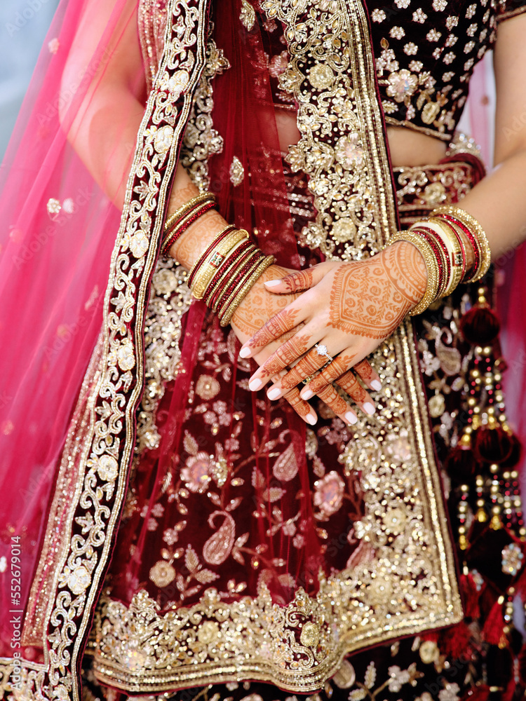 Beautiful woman in traditional Indian wedding dress with golden accessories and hand drawings on hands with an engagement silver ring
