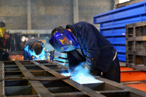 Workers wearing industrial uniforms and Welded Iron Mask at Steel welding plants, industrial safety first 