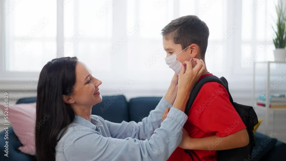 Mother helping son to put his face mask on before school, pandemic precautions Mother helping son to put his face mask on before school, pandemic precautions
