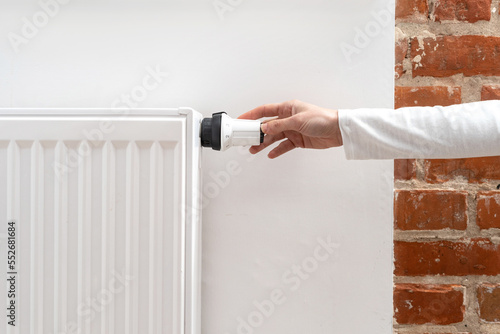 Woman turning on heating equipment in room