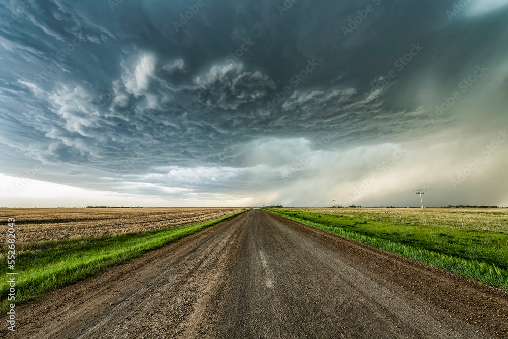Gravel road leading into the distance towards dramatic storm clouds; Val Marie, Saskatchewan, Canada Gravel road leading into the distance towards dramatic storm clouds; Val Marie, Saskatchewan, Canada