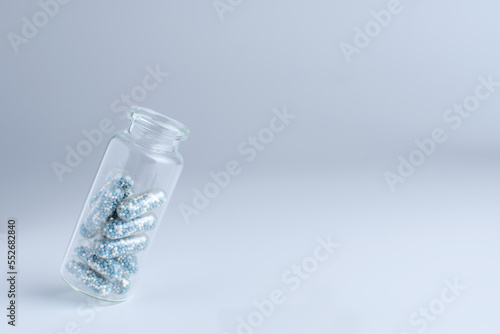 glass medical bottle with blue pills inside
