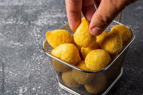 male hand picking up 'salgadinho de festa' or brazilian traditional party snack. a mix made of coxinha, bolinha de queijo and risolis. on a frying basket photo