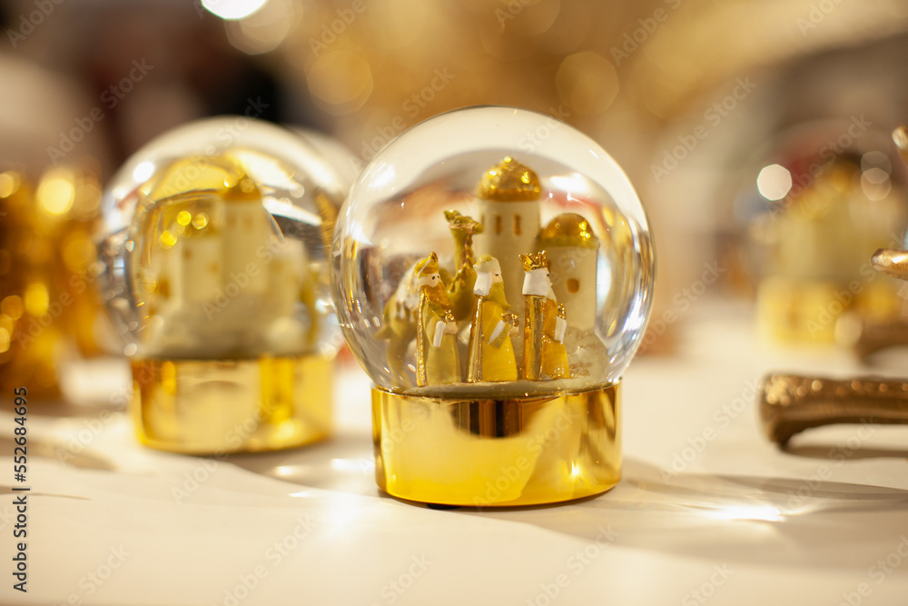 Shiny festive golden snow globes with three kings to celebrate Spanish traditional holiday on the shelf of Christmas store or market