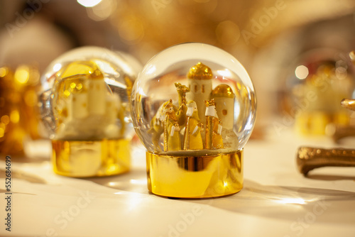 Shiny festive golden snow globes with three kings to celebrate Spanish traditional holiday on the shelf of Christmas store or market