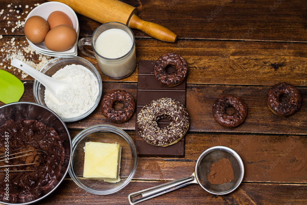 Preparing doughnuts at home. Ingredients for donuts such as eggs, milk, chocolate, pudding, butter, cacao, flour, rolling pin, cake pan, grater, egg beater, spatula Preparing doughnuts at home. Ingredients for donuts such as eggs, milk, chocolate, pudding, butter, cacao, flour, rolling pin, cake pan, grater, egg beater, spatula