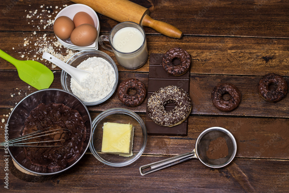 Preparing doughnuts at home. Ingredients for donuts such as eggs, milk, chocolate, pudding, butter, cacao, flour, rolling pin, cake pan, grater, egg beater, spatula Preparing doughnuts at home. Ingredients for donuts such as eggs, milk, chocolate, pudding, butter, cacao, flour, rolling pin, cake pan, grater, egg beater, spatula