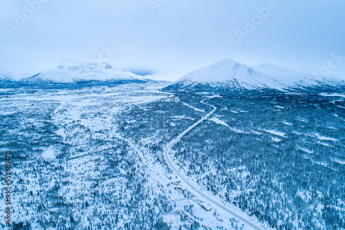 The South Klondike highway winds its way through the wintry Yukon landscape with forests and snow-capped mountain peaks; Carcross, Yukon, Canada photo