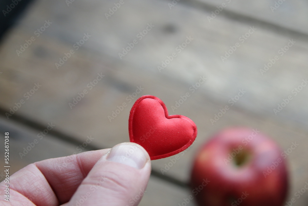 Hand holding a heart on the background of an apple healthy food concept. Hand holding a heart on the background of an apple healthy food concept.