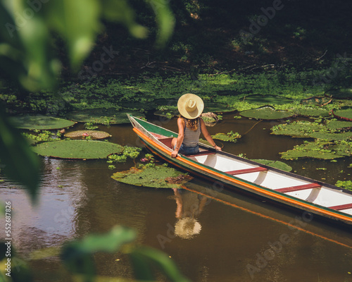 Mulher não identificada, de costas, com chapéu, em barco no rio croa, cercado de vitórias-régias, em cruzeiro do sul, Acre  photo