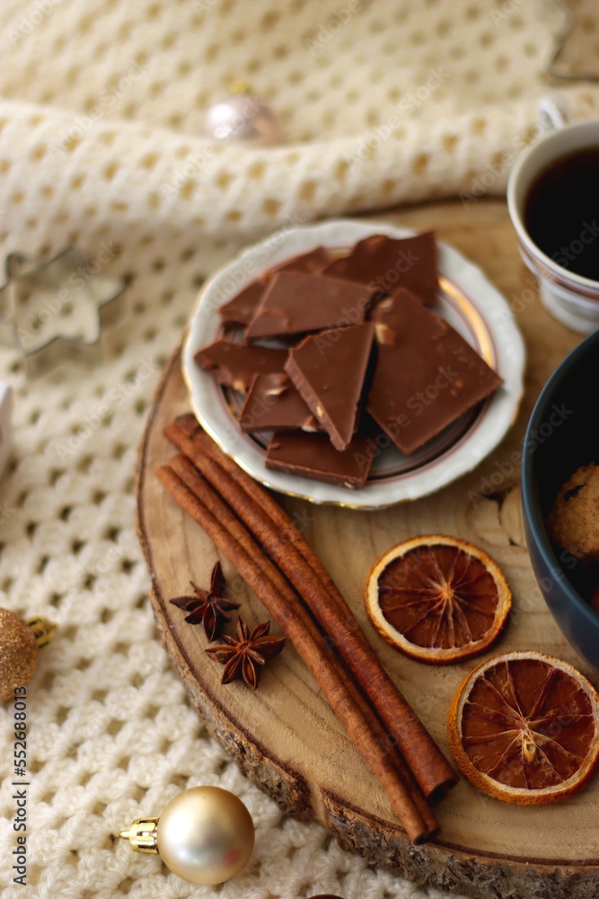 Fototapeta premium Various Christmas decorations, cup of tea or coffee, sweets, small presents, knitted blanket and candles. Selective focus.