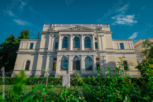 Front facade of national museum of bosnia and herzegovina on a summer day hiding behind some greenery.