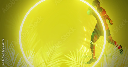 African american rugby player running by illuminated circle and plants over yellow background