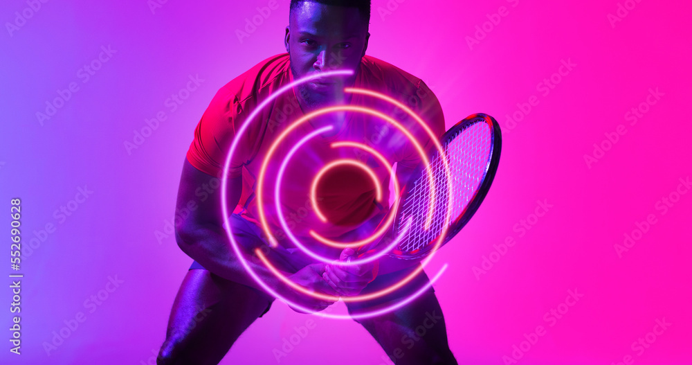 Illuminated circular pattern over african american tennis player holding racket on pink background Illuminated circular pattern over african american tennis player holding racket on pink background