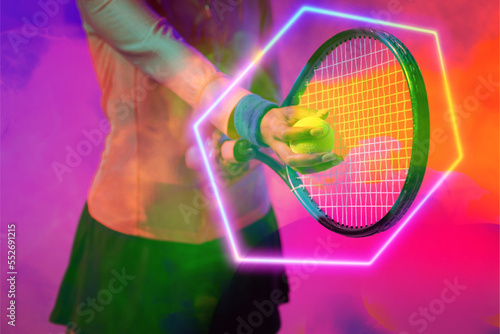 Midsection of african american female tennis player serving ball with racket by illuminated hexagon