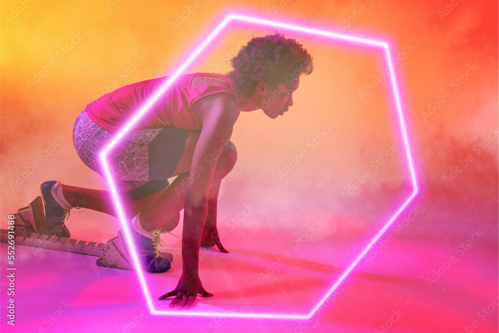 African american female athlete at starting position by illuminated hexagon on gradient background