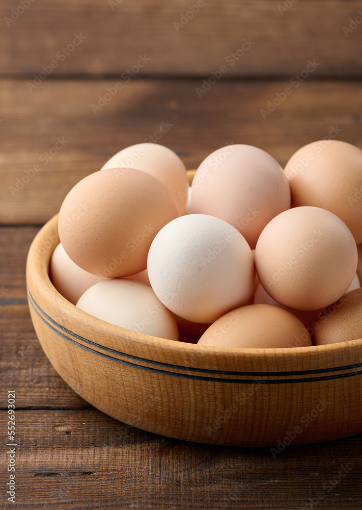 Fresh brown chicken eggs in a round wooden plate on the table Fresh brown chicken eggs in a round wooden plate on the table